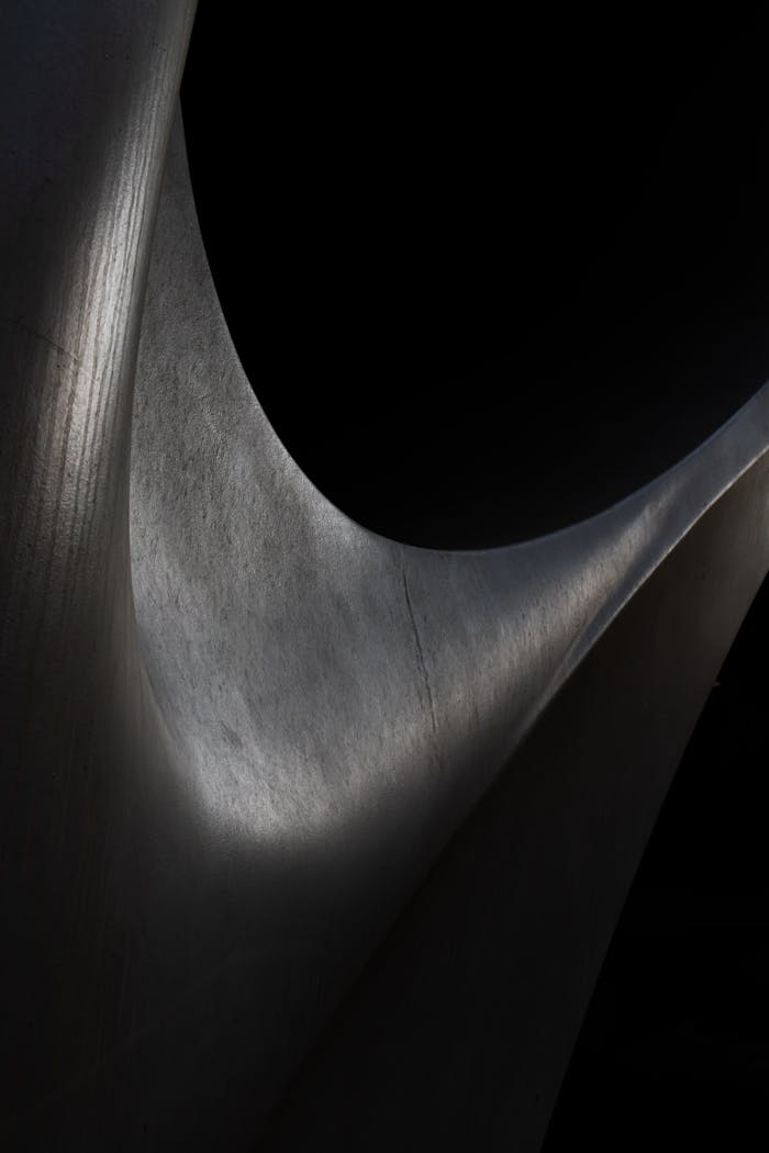 Explore the intricate play of light and shadow on metal curves in this abstract art piece.